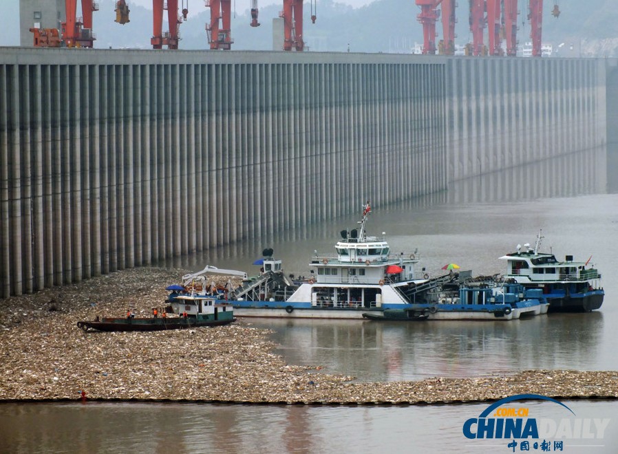 长江洪水带来大量漂浮垃圾三峡大坝前工人忙打捞
